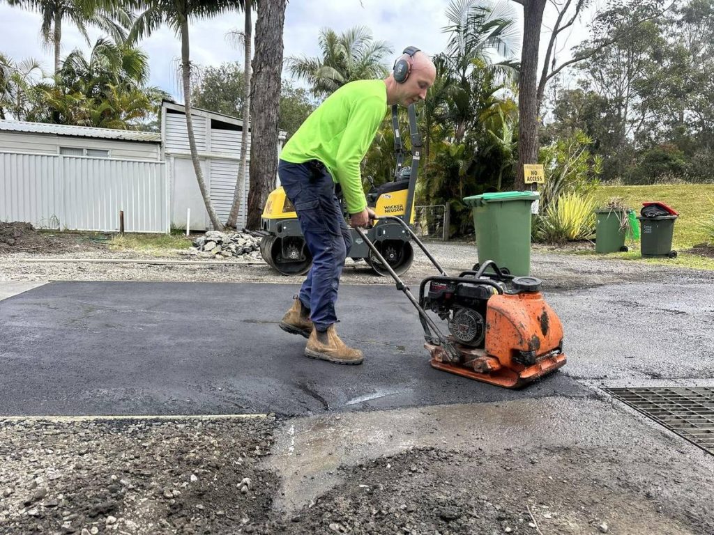 Compacting a hot-mix asphalt patch repair next to a drain grate