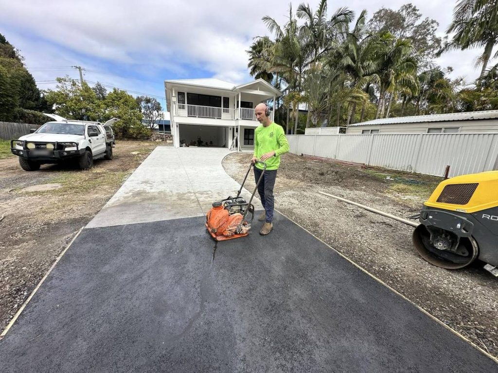 New asphalt driveway being compacted next to a concrete driveway on the Central Coast